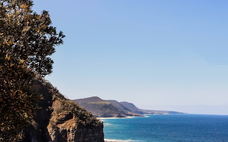 Australian coastal highway curve under clear blue skies.